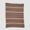 The in2green Geometric Stripe Throw Blanket is crafted from recycled cotton and showcases horizontal brown, tan, and orange patterns. This eco-friendly throw is displayed flat against a plain background.