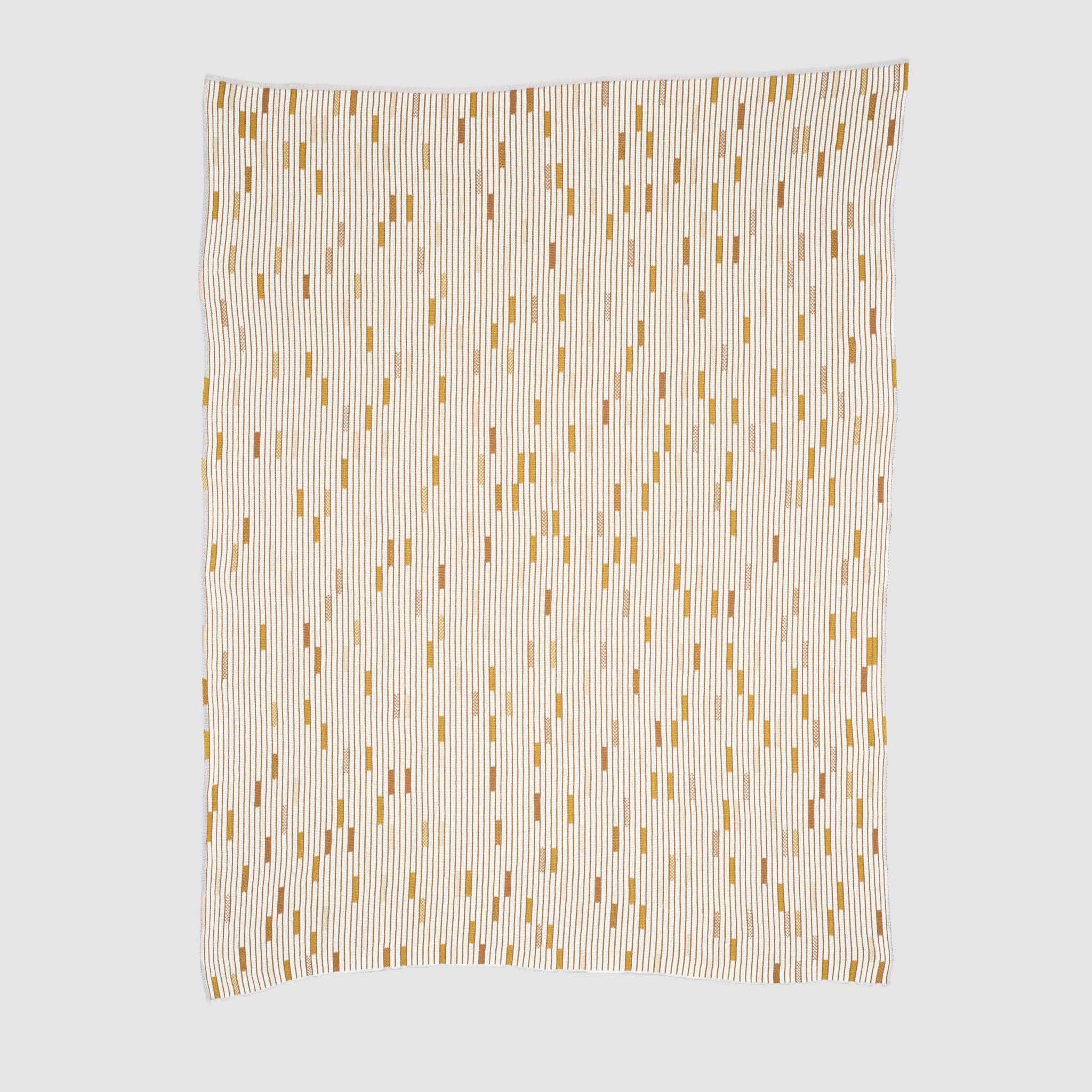 The Matrix Throw Blanket by Elodie Blanchard for in2green is a rectangular, recycled cotton throw featuring vertical black lines and scattered yellow and orange rectangles, shown flat on a light background.