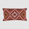 The New Horizon Lumbar Pillow by in2green features a rectangular Southwestern design with geometric patterns in red, green, black, and white—ideal for introducing modern rustic decor to any space.