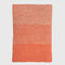 The in2green Textured Ombre Throw Blanket features a rectangular, ribbed design in two-tone orange, woven from recycled cotton and displayed flat on a white background.