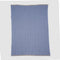 The in2green Poly Herringbone Edge Throw Blanket is a rectangular blue and white striped outdoor throw with a subtle herringbone knit and beige borders, made from recycled polyester, shown flat on a white background.