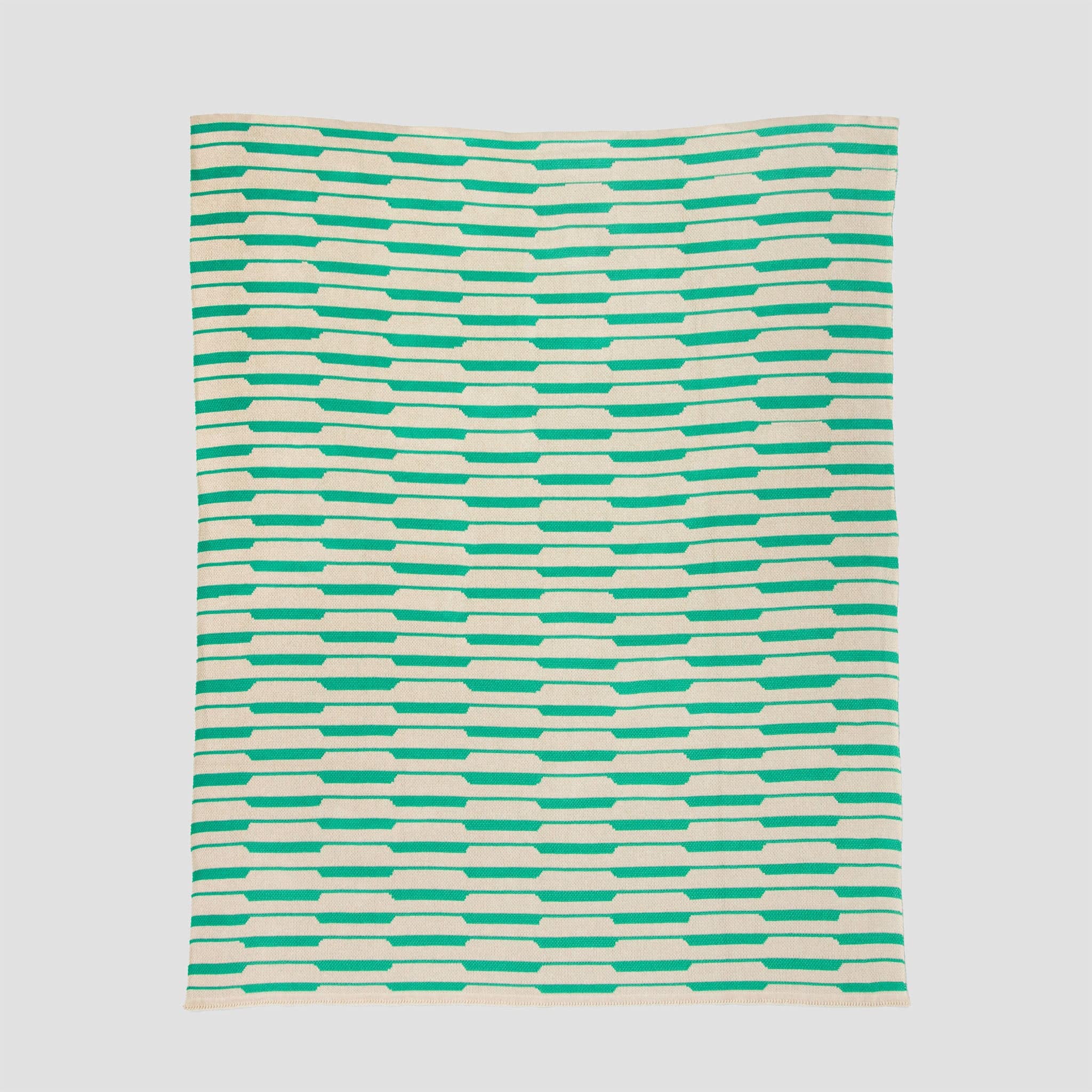 The Riata Throw Blanket by Petra Kaksonen for In2Green features a Scandinavian-inspired design with horizontal green and beige rectangles on a light background—perfect for stylish, sustainable home decor.