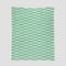 The Riata Throw Blanket by Petra Kaksonen for In2Green features a Scandinavian-inspired design with horizontal green and beige rectangles on a light background—perfect for stylish, sustainable home decor.