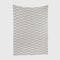 The Riata Throw Blanket by Petra Kaksonen is a rectangular white blanket with staggered rows of beige rectangles, inspired by Scandinavian heritage.