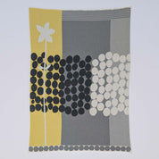 Rock Rose by Susy Pilgrim Waters for In2Green is a modern rectangular textile in yellow, gray, black, and white with abstract dots, grid designs, a vertical white flower, and made from a sustainable cotton blend.
