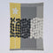 Rock Rose by Susy Pilgrim Waters for In2Green is a modern rectangular textile in yellow, gray, black, and white with abstract dots, grid designs, a vertical white flower, and made from a sustainable cotton blend.