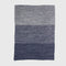 The in2green Textured Ombre Throw Blanket features a ribbed texture with horizontal color blocks in grey and blue, crafted from recycled cotton and shown on a plain white background.