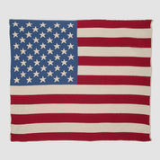 The in2green Hometown Pride Flag - Cotton Sustainable Knit Blanket is a rectangular, USA-made fabric that features the design of the United States flag with 50 white stars and 13 alternating red and white stripes.