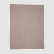 The in2green 100% Merino Wool Links Throw Blanket is a minimalist, light brown throw with a white border, crafted from soft wool and displayed flat on a light grey background.