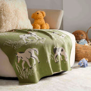 The In2Green Baby Farm Blanket is draped over a white chair in the nursery, featuring playful farm designs with stuffed animals and a wicker basket in the background.