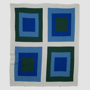 Explore the Bauhaus Throw Blanket by in2green, featuring a Bauhaus-inspired pattern of four squares layered with shades of blue and green on a light grey background. This design highlights an eco-friendly approach, seamlessly blending art with sustainability.
