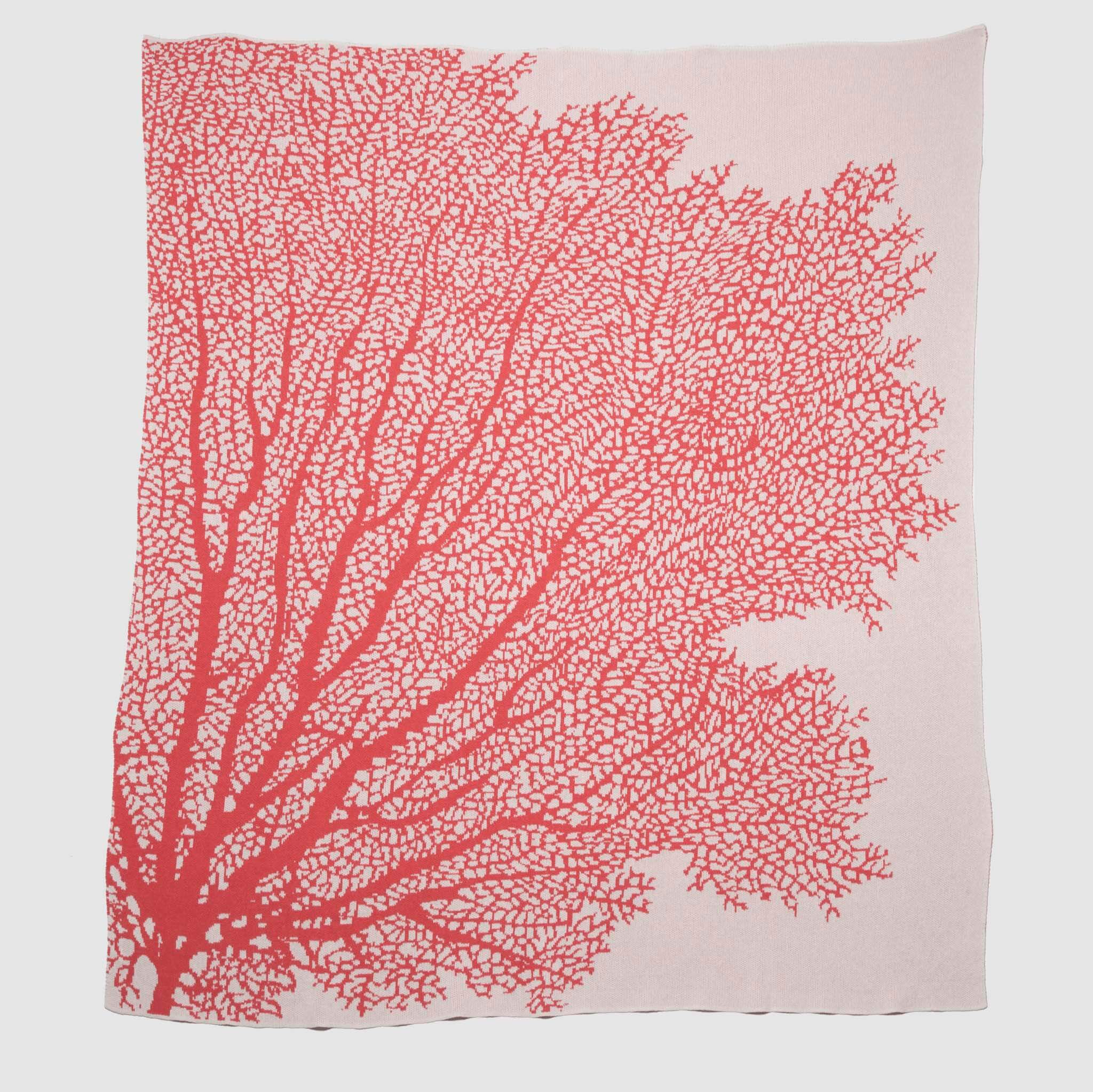 The in2green Fan Coral Throw Blanket features a light pink fabric with a bold red coral branch design—ideal for adding coastal style to beach houses or as a chic accent piece.