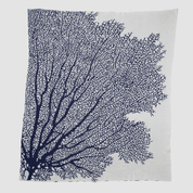 The Fan Coral Throw Blanket by in2green features white fabric adorned with a dark blue, coral-like pattern branching from the bottom left, perfect for enhancing coastal style in beach houses.