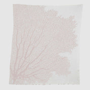 The in2green Fan Coral Throw Blanket features a white fabric with a light pink coral pattern—ideal for adding coastal charm to your beach house décor.