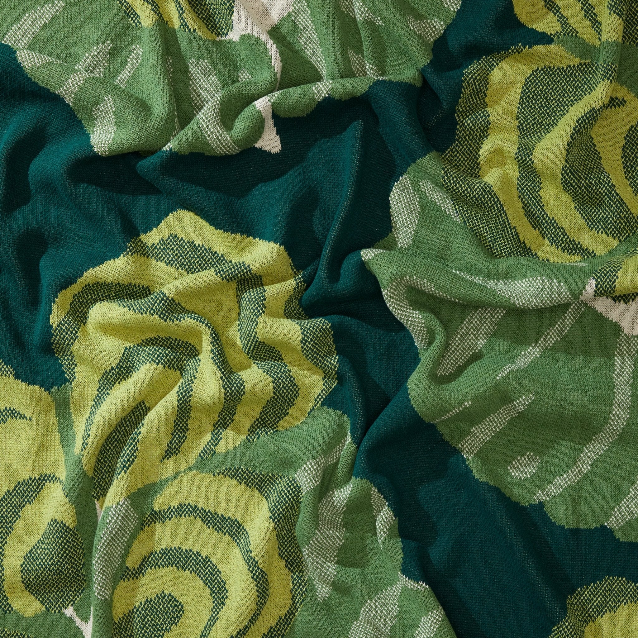 Close-up of the Floréal 7 Throw Blanket by E.A. Seguy for in2green, showcasing bold green and yellow colors with an Art Nouveau-inspired floral design and visible folds.