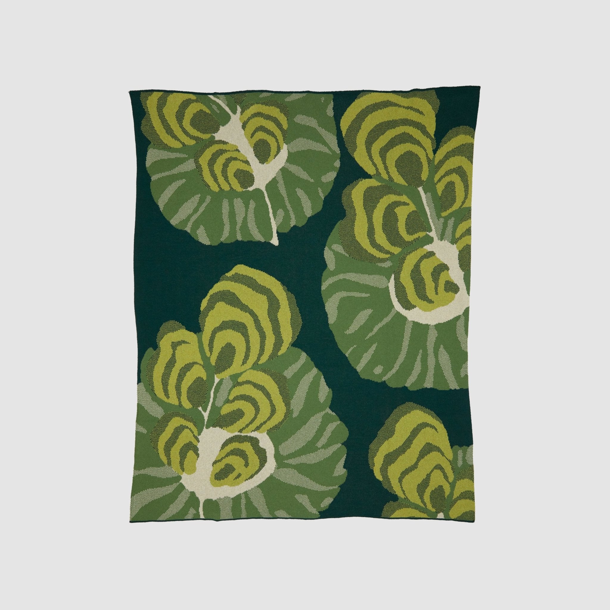 The Floréal 7 Throw Blanket by E.A. Seguy from in2green showcases a dark green background with large, abstract green and yellow leaf patterns reminiscent of Art Nouveau style.