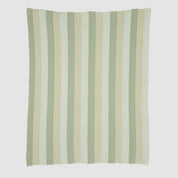 The Herringbone Hues Throw Blanket by In2Green is made in the USA from recycled cotton, featuring a white background with patterned vertical stripes in green, beige, and light gray.