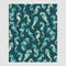 The in2green Seahorse Watercolor Throw Blanket showcases seahorses in blue and beige on a dark teal background, crafted from recycled cotton.