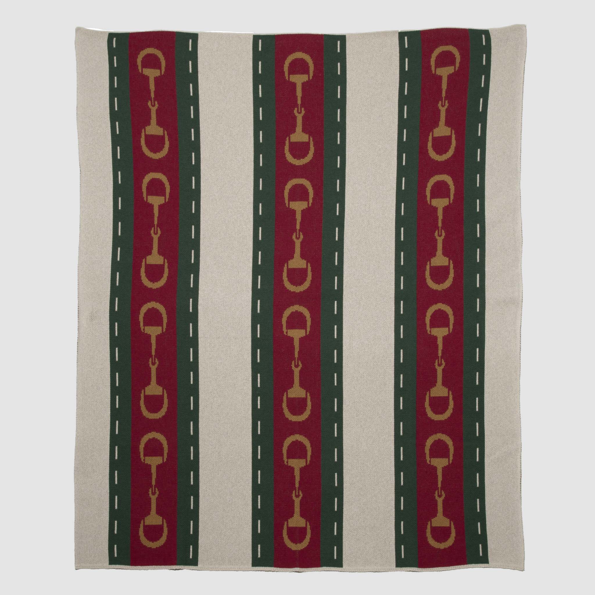 Part of the in2green equestrian collection, the Striped Horse Bit Throw Blanket is a recycled cotton square featuring vertical red, green, and beige stripes with gold horse bit accents along the red stripes.