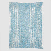 Presenting the Warrior Throw Blanket Teal by In2Green, a rectangular cloth featuring a stylish blue and white herringbone pattern set against a white background, perfect for providing comfort during chemotherapy sessions.