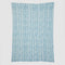 Presenting the Warrior Throw Blanket Teal by In2Green, a rectangular cloth featuring a stylish blue and white herringbone pattern set against a white background, perfect for providing comfort during chemotherapy sessions.